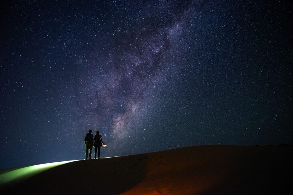 Two people looking at the Milky Way at night
