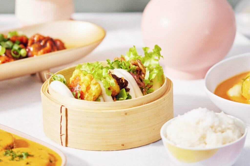Picture of a bamboo steamer with three boa buns with crispy tofu and lettuce