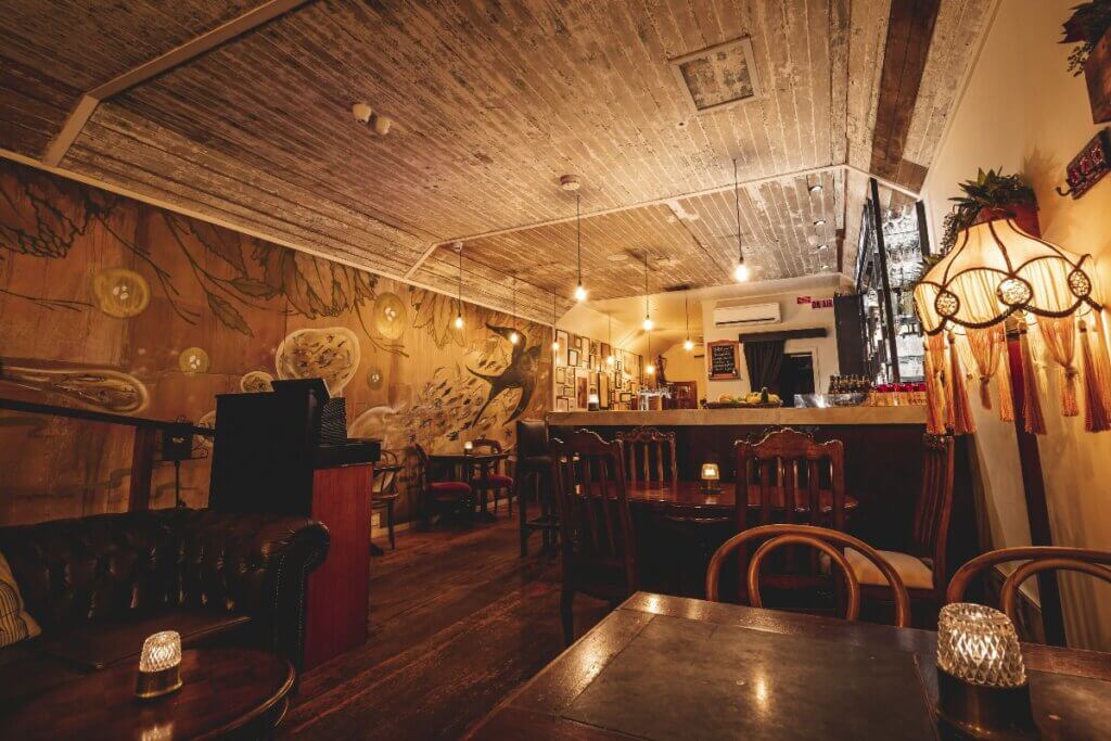 Canvas Club interior with murals on the wall, wooden slatted ceilings and ambient lighting.