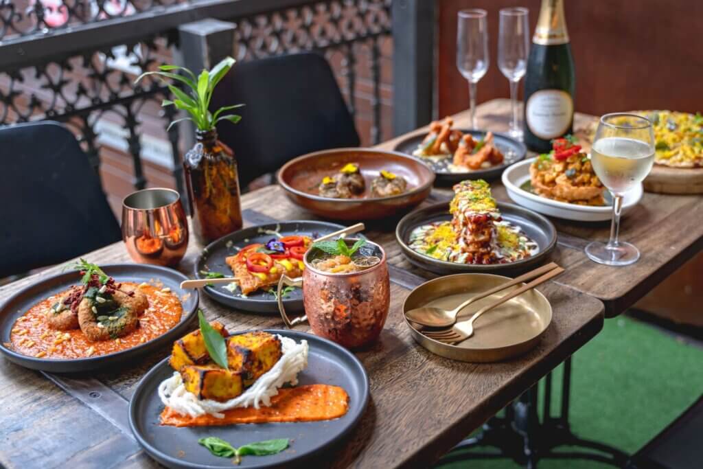 Spread of curry dishes, cocktails and bubbly at an Indian restaurant.